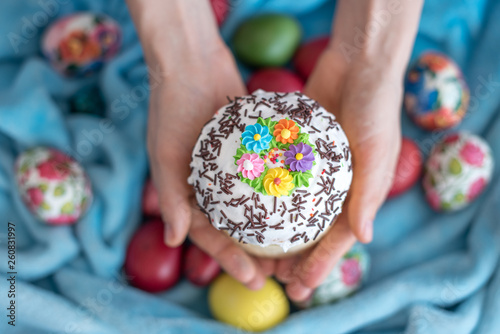 Easter cake with decorations and in hands on the background of assorted colored eggs