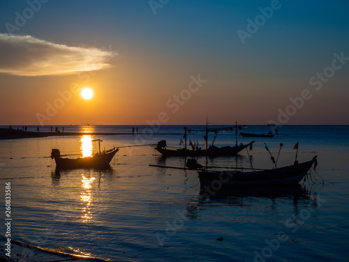 Silhouette of a fishing boat in the rays of the setting sun with clouds. Ko Phangan.Thailand. © alexkazachok