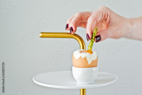 Hand chef inserts a trickle of asparagus in a boiled egg