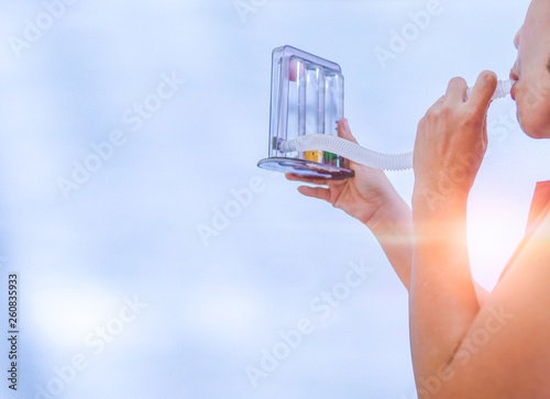 woman holding triflow and deep breathing to improve lung expansion, woman patient with chest rehabilitation by triflow device photo