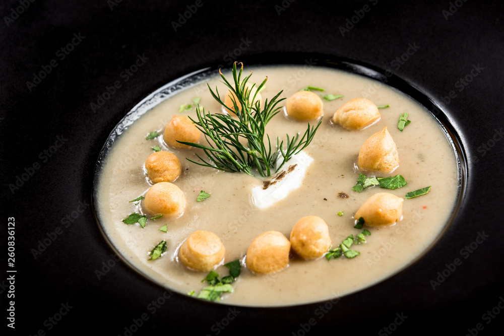 Homemade mushroom cream soup served on dark plate Homemade mushroom cream soup served on dark plate