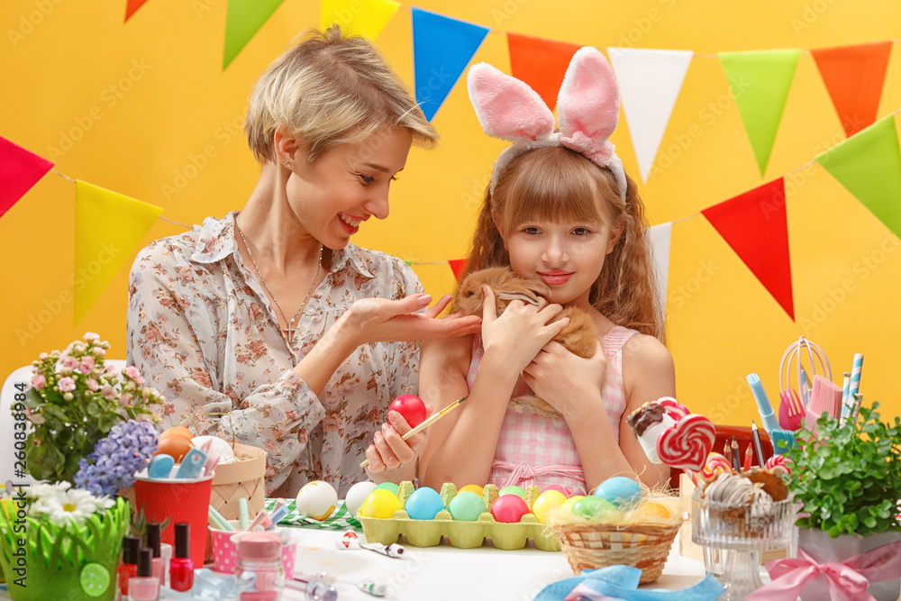 happy family mother and child girl paints eggs for Easter at home. Family celebration and home decoration for spring holiday. happy family mother and child girl paints eggs for Easter at home. Family celebration and home decoration for spring holiday.