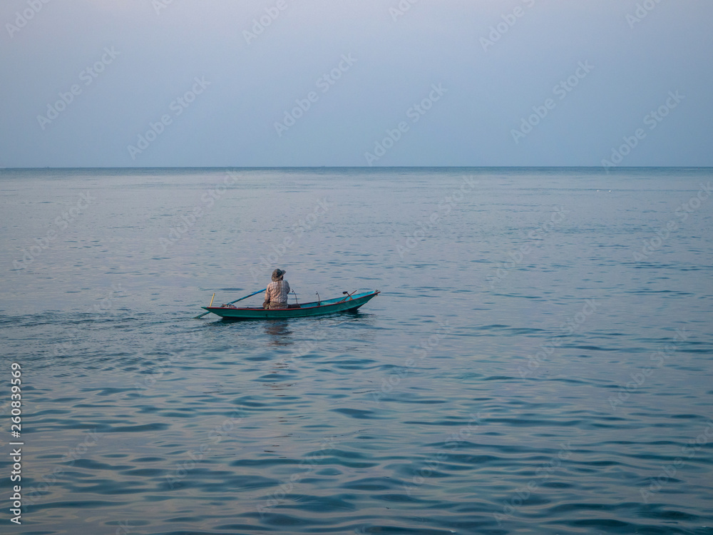 Silhouettes of people in a kayak in the rays of the setting sun against the background of clouds. Ko Phangan.Thailand.