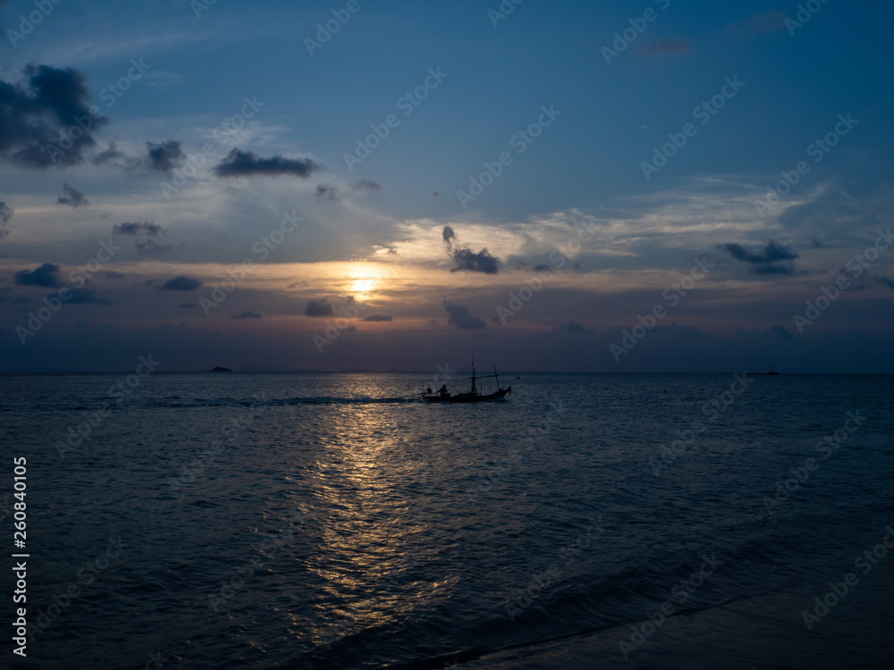 Silhouettes of people in a kayak in the rays of the setting sun against the background of clouds. Ko Phangan.Thailand. Silhouettes of people in a kayak in the rays of the setting sun against the background of clouds. Ko Phangan.Thailand.
