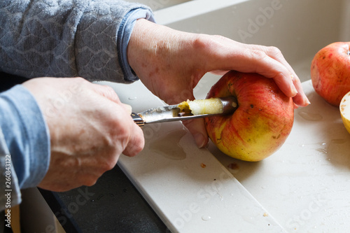 Hands of a woman removing an apple core with an apple corer in a kitchen