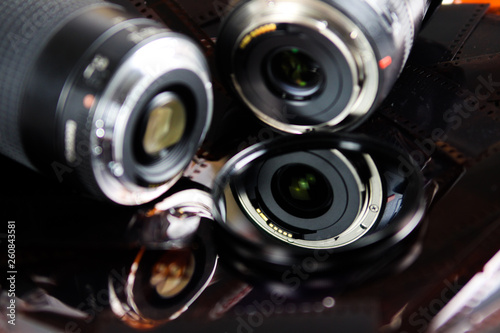 Close up of two camera lenses with isolated circular filter on negative film strips © Ralf