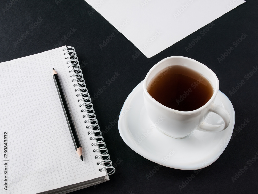 Office concept. Black pencil, blank notebook and white cup with coffee on black and white paper background. Top view. Copy space Office concept. Black pencil, blank notebook and white cup with coffee on black and white paper background. Top view. Copy space