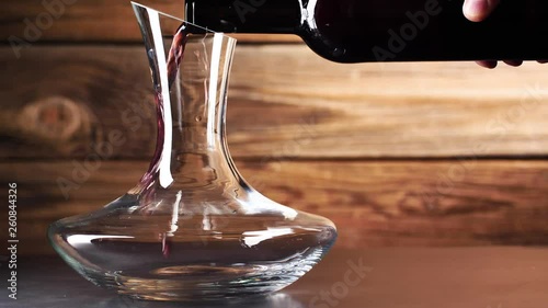 Wein. Rotwein, der in Weinglas über dunklem Hintergrund gießt.