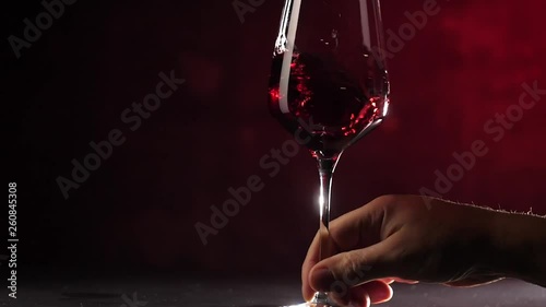 Wine. Red wine pouring in wine glass over dark background. 
