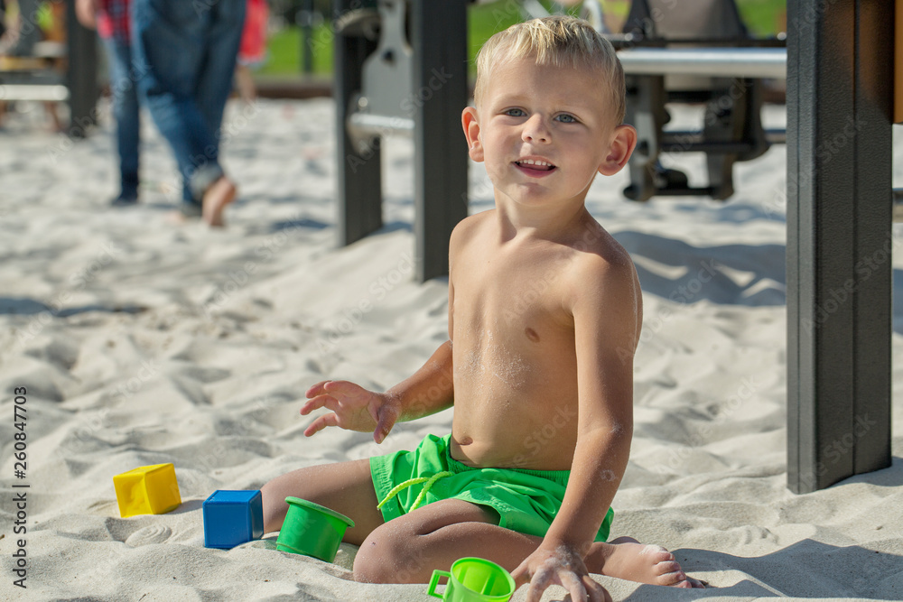 Fototapeta premium The boy plays in the sandbox