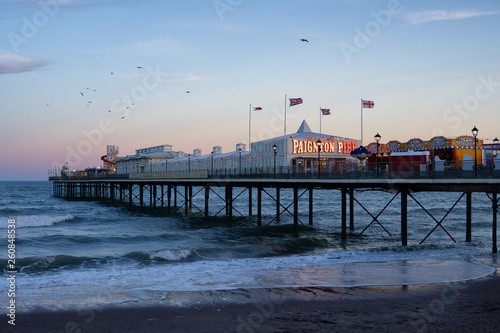 A view of Paignton Pier, Devon from the beach with the waves beneath at sunset. Shot in Torbay.