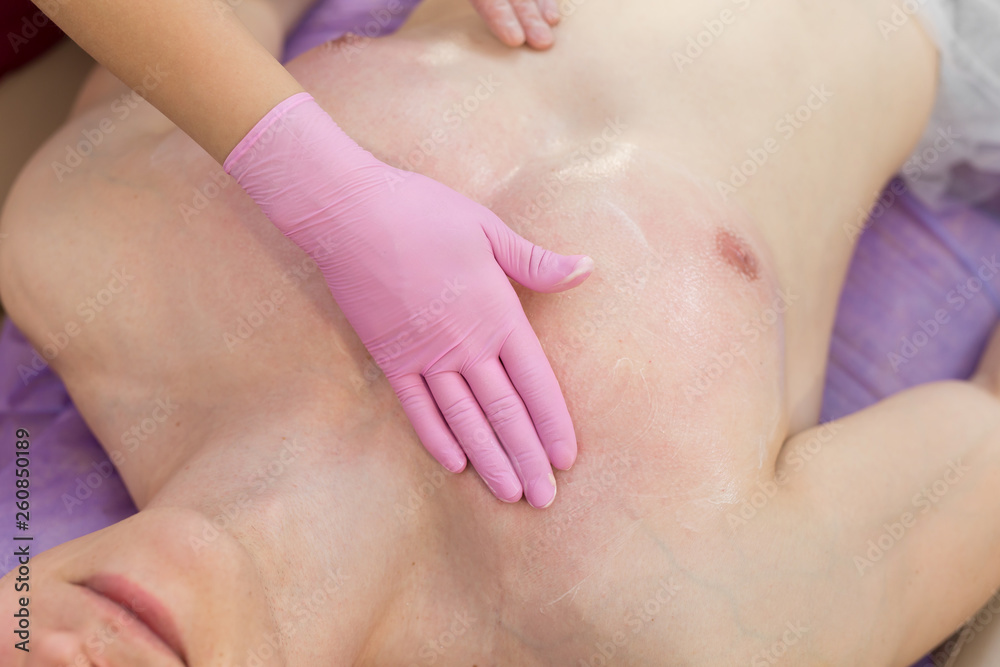 Beautician applies a moisturizer to the chest of a muscular man after the hair removal procedure. Sugaring Beautician applies a moisturizer to the chest of a muscular man after the hair removal procedure. Sugaring