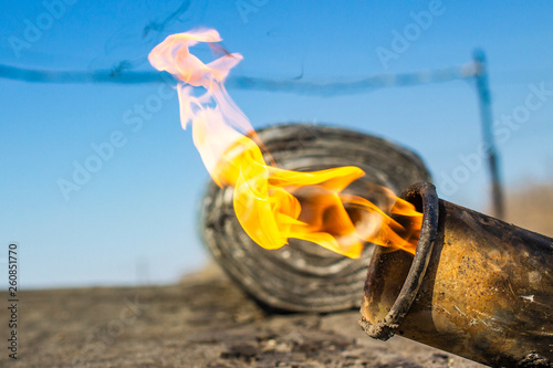 gas burner with fire and roll of roofing material on blurred background with bokeh effect