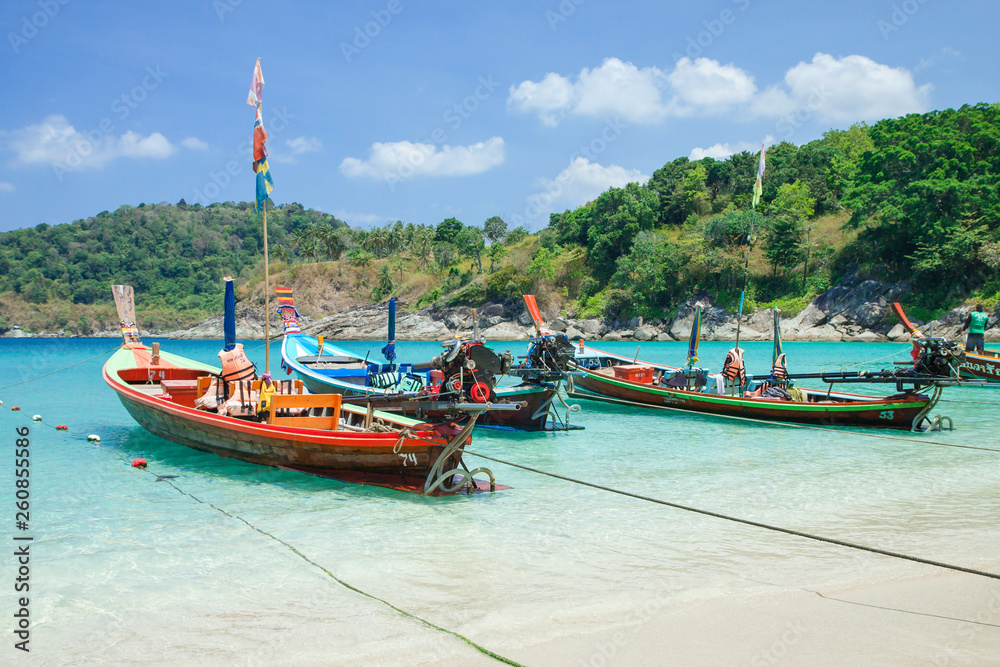 Beautiful exotic boats in lagoon. Seascape with transparent azure water and coast with tropical forest. Thailand. Andaman Sea. 