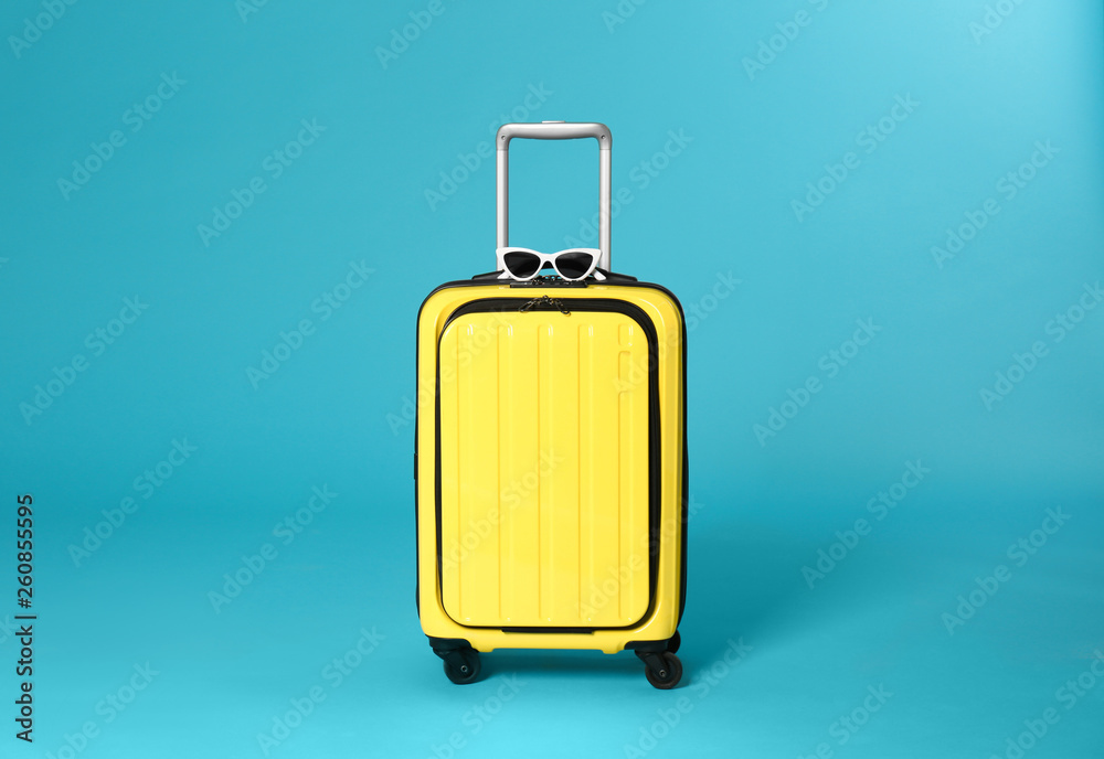 Stylish suitcase with sunglasses on color background Stylish suitcase with sunglasses on color background