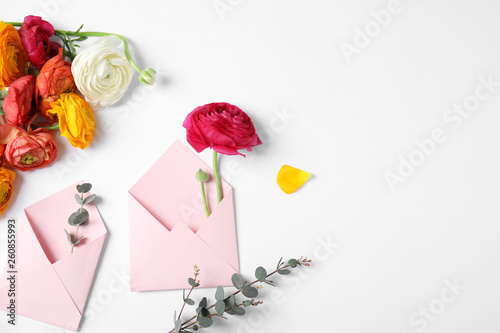 Composition with beautiful ranunculus flowers and envelopes on white background