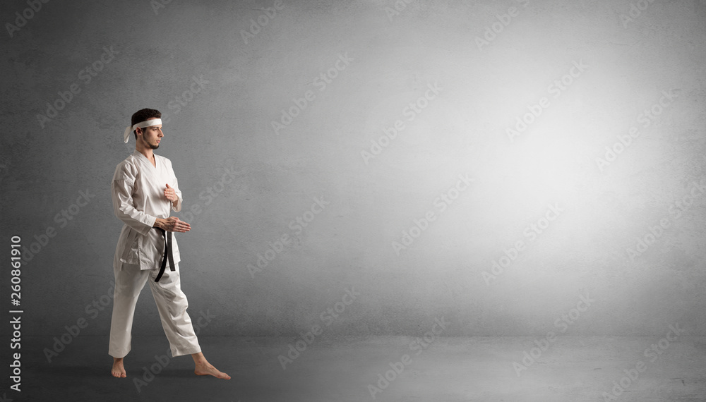 Small karate man fighting in an empty grey copy space Small karate man fighting in an empty grey copy space