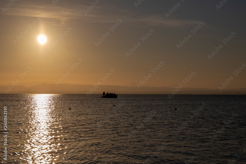 Boat with people in Albufera of Valencia at sunset.