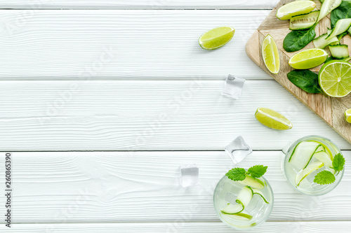 summer cocktails for freshness with lime, mint, cucumber and spinach and ice on white background top view mockup
