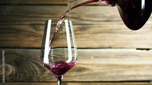 Wein. Rotwein, der in Weinglas über dunklem Hintergrund gießt. photo