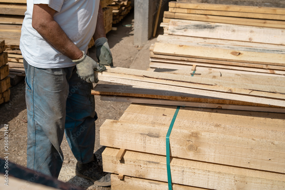 Close up on the worker holding building material planks loading at the warehouse for the construction site Close up on the worker holding building material planks loading at the warehouse for the construction site