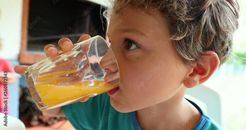Child boy drinking orange juice and eating breakfast in the morning