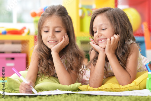 Portrait of two cute little girls drawing together