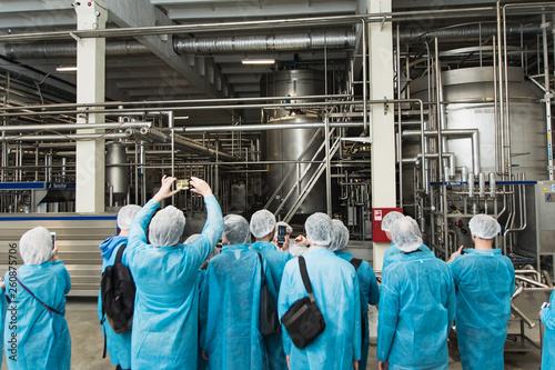 excursion at the factory. People in protection, shoe covers, blue overalls stand and listen to a tour of the metal brewery. People Photograph production on the phone photo