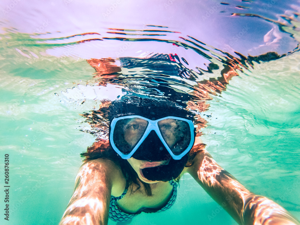 Naklejka premium woman taking an underwater selfie while snorkeling in crystal clear tropical water