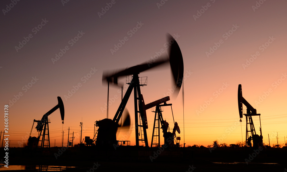Oil pumps in action, silhouetted against the setting sun
