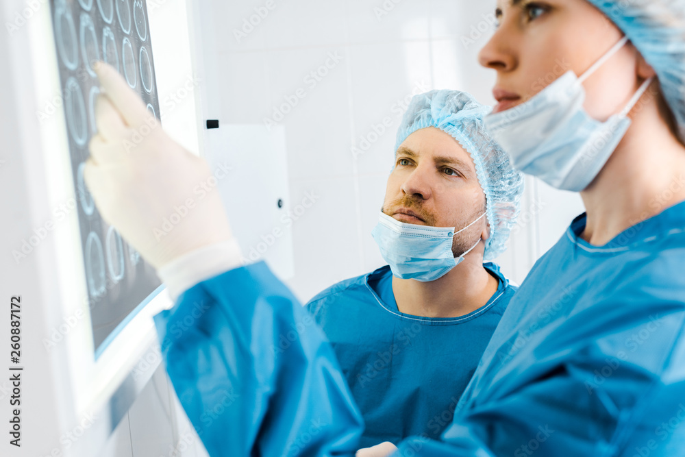 selective focus of doctors in uniforms looking at x-ray in clinic selective focus of doctors in uniforms looking at x-ray in clinic