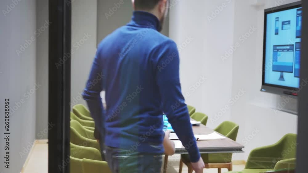 Manager walking along corridor and entering office where young web designer presenting him website template on laptop, digital board and smartphone Manager walking along corridor and entering office where young web designer presenting him website template on laptop, digital board and smartphone