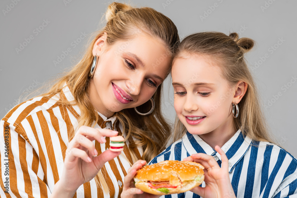 Appealing good-looking positive girls comparing different sizes of burgers