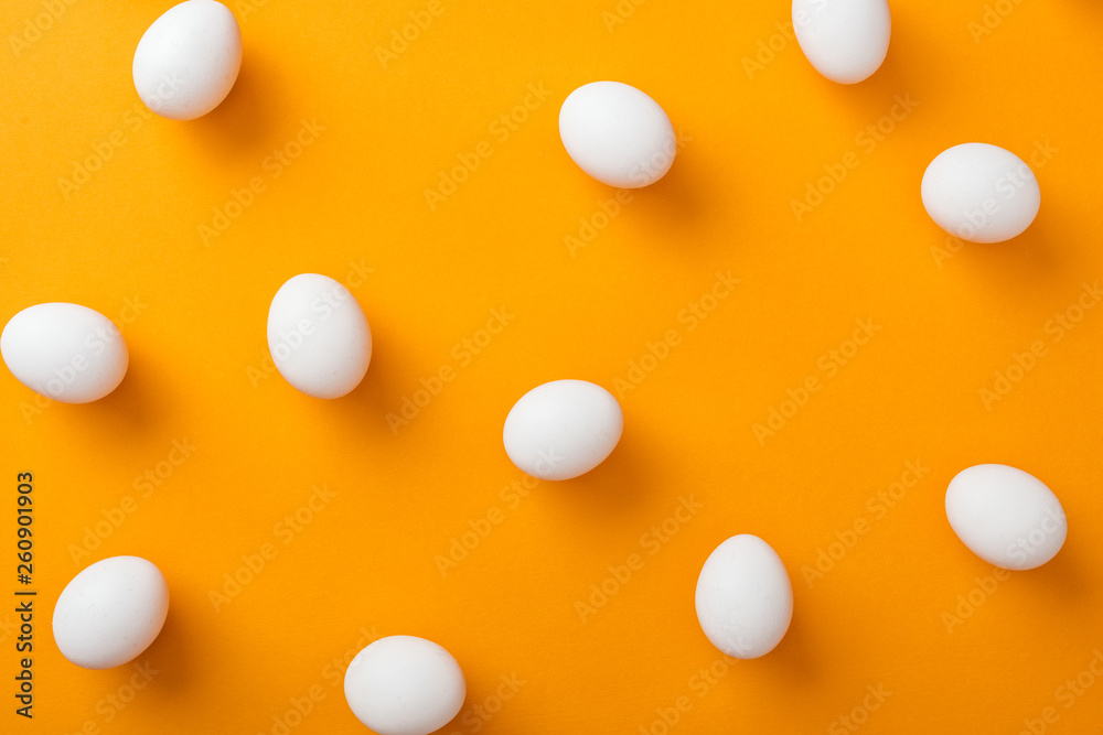 top view of whole white fresh chicken eggs on bright orange background top view of whole white fresh chicken eggs on bright orange background
