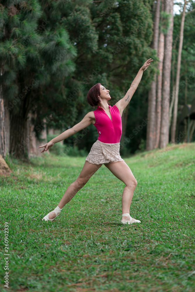 Happy redhead smiling girl dancing in a green park on Brazil in a summer day