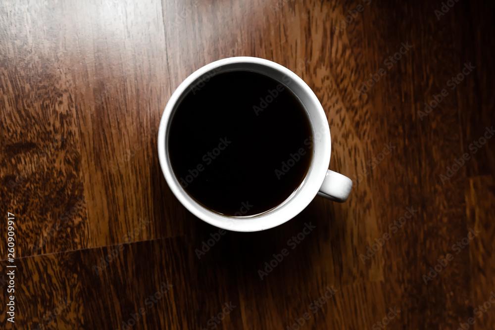 Black coffee in white cups by hand on wooden floors and coffee beans Black coffee in white cups by hand on wooden floors and coffee beans