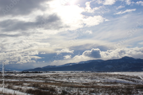 Cold cloudy day over the mountains , Winter time in the north snow covered sagebrush and the sun is shining through white clouds