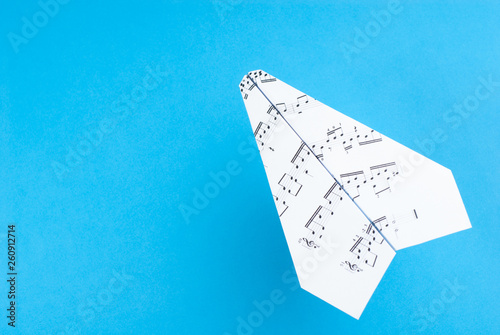 Paper jet /paper airplane made of a music score. Music score paper plane on blue.