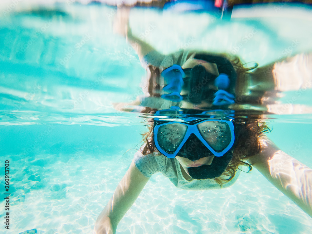 Naklejka premium woman taking an underwater selfie while snorkeling in crystal clear tropical water