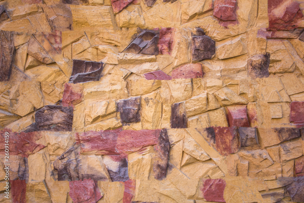 Naklejka premium yellow stone wall with red brown and gray spots and deep relief. rough surface texture