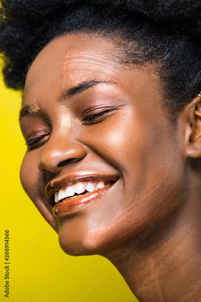 Fototapeta premium Happy laughing african american woman with closed eyes isolated on yellow
