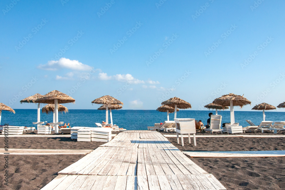 Beautiful view of the Mediterranean Sea from the sandy beach of the island of Crete. On the beach, people sunbathe on the lounge chairs
