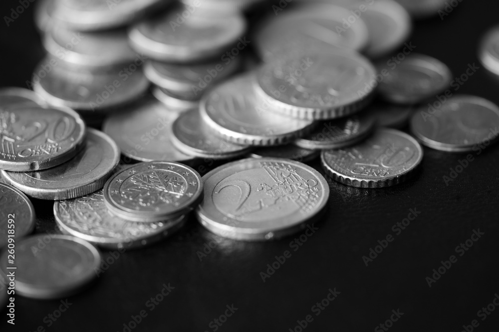 Euro coins scattered on a dark background close up. Black and white Euro coins scattered on a dark background close up. Black and white