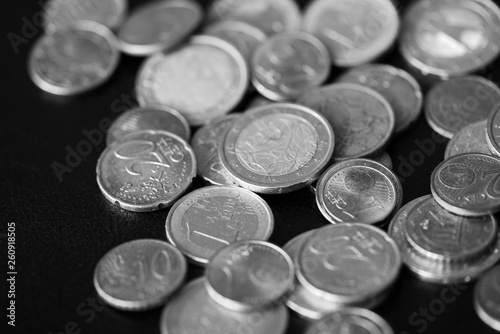 Euro coins scattered on a dark background close up. Black and white