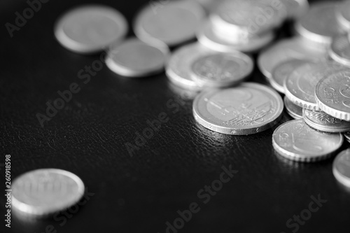 Euro coins scattered on a dark background close up. Black and white