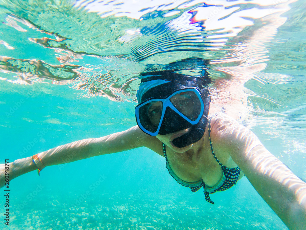 Naklejka premium woman taking an underwater selfie while snorkeling in crystal clear tropical water