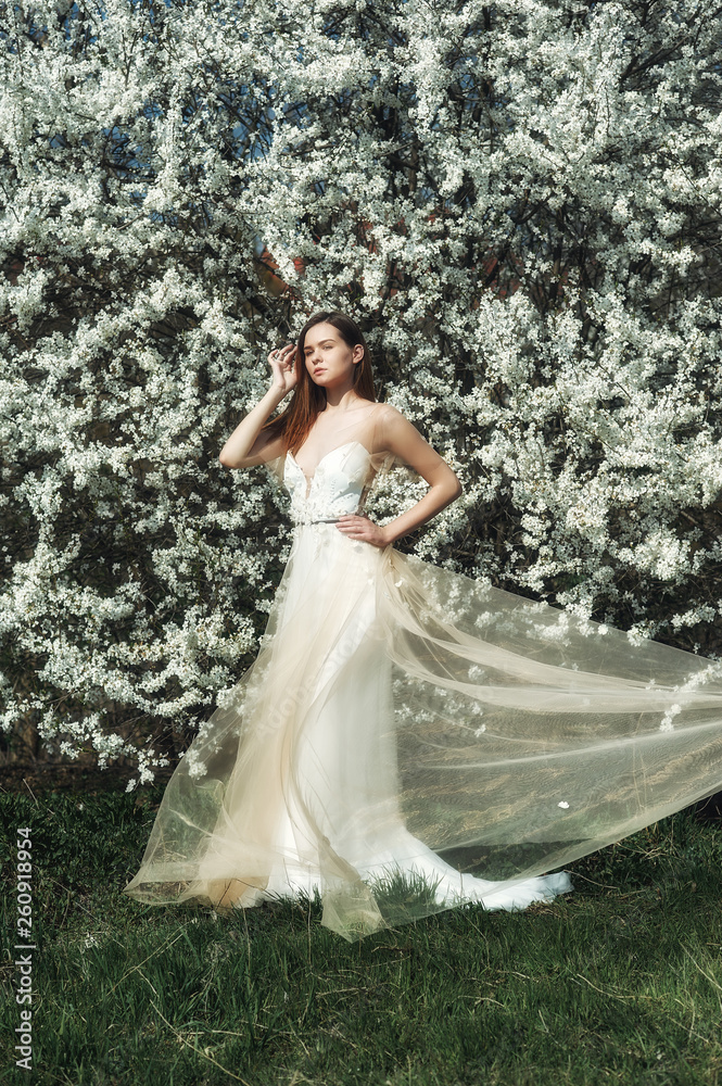 Portrait of a young beautiful fashionable woman in an evening dress . Girl posing in a blooming garden