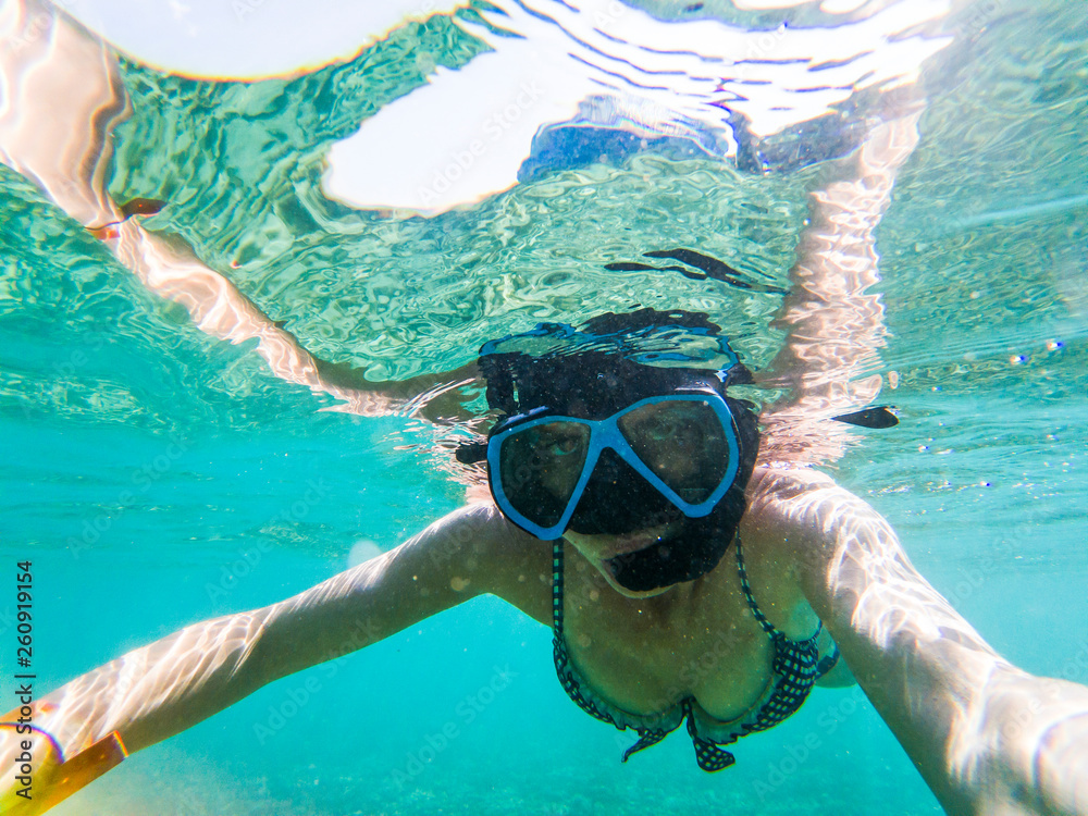 woman taking an underwater selfie while snorkeling in crystal clear tropical water