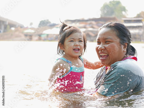 Little Asian baby girl  25 months old  enjoys playing water in a river with her auntie - playing outdoor and engaging with nature provides positive impact on baby s health and development