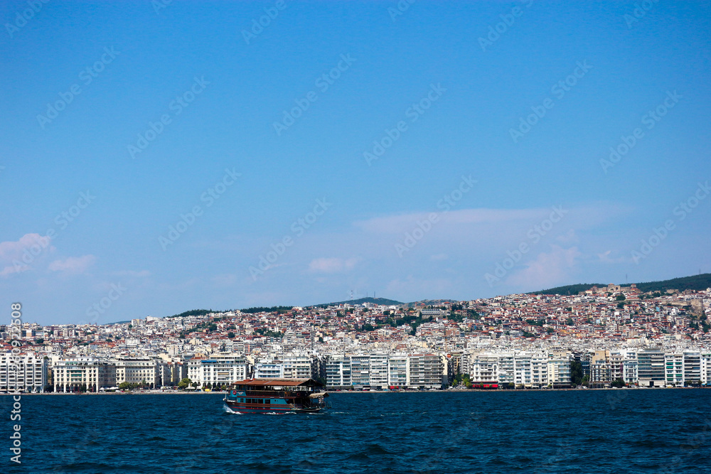 Boat in mediterranean sea with city of Thessaloniki on the background in warm summer day